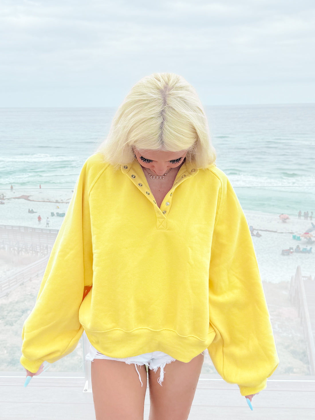 Lemon yellow pullover sweatshirt styled at the beach.
