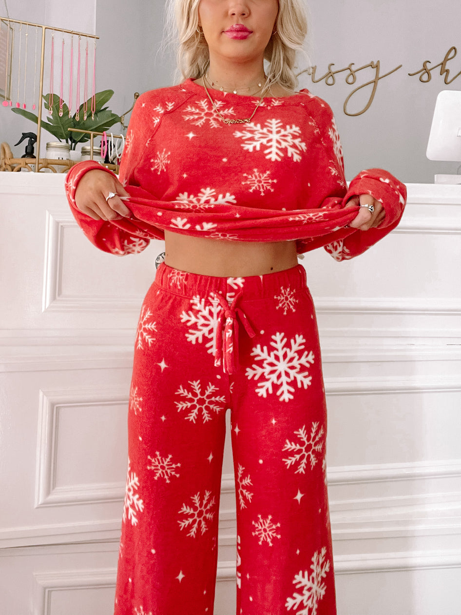 Red fleece pajama set with white snowflake pattern; cozy holiday sleepwear.
