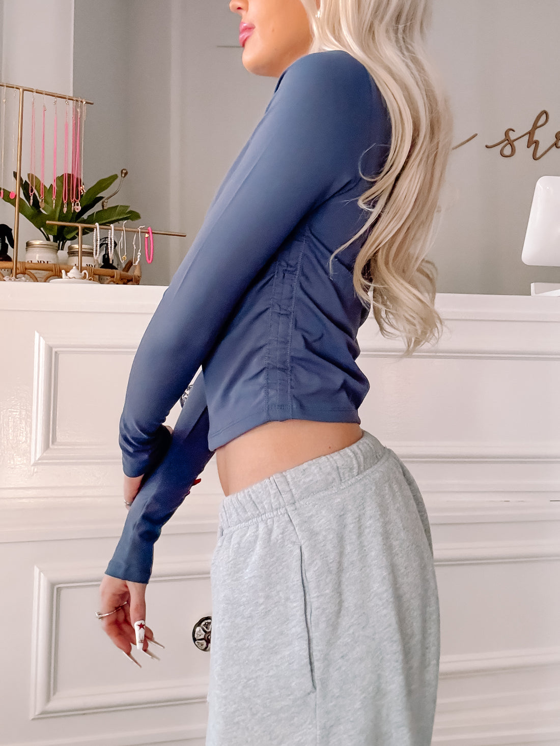 Side view of a fitted, long-sleeved navy blue cropped top on a model, showcased against a light background.
