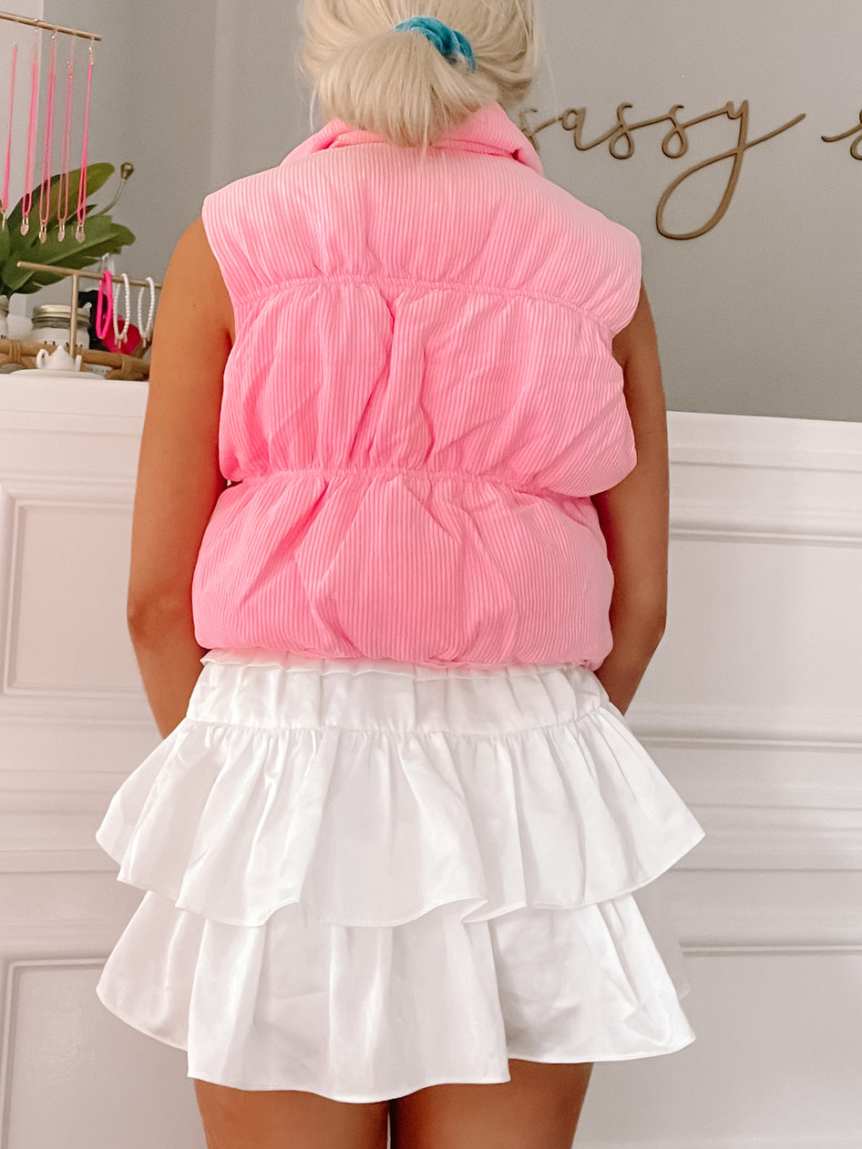 Light pink quilted vest with a sleeveless design, shown from the back.
