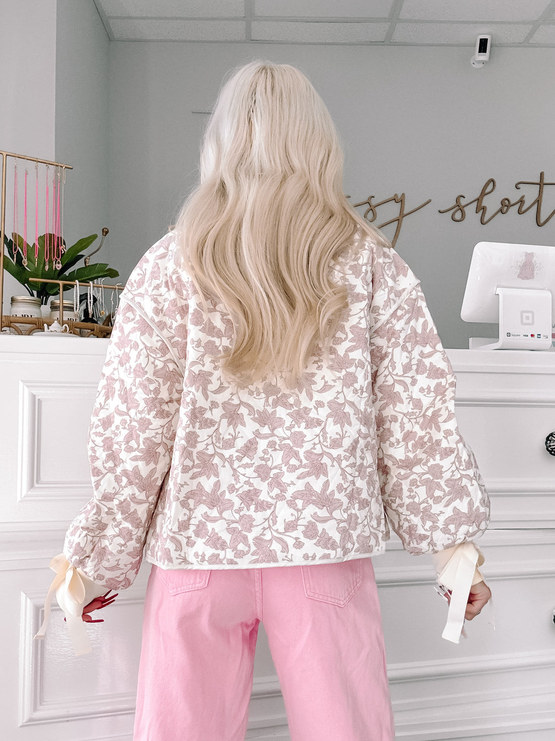 Cream quilted jacket with a mauve floral print, featuring puff sleeves and satin ribbon detailing.
