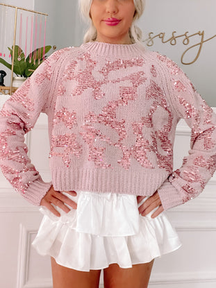 Pink sequined sweater styled with a white ruffled skirt.
