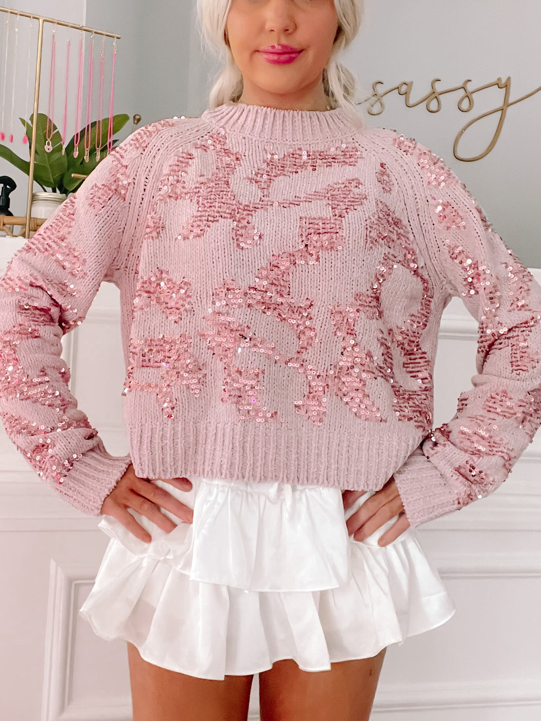 Pink sequined sweater styled with a white ruffled skirt.
