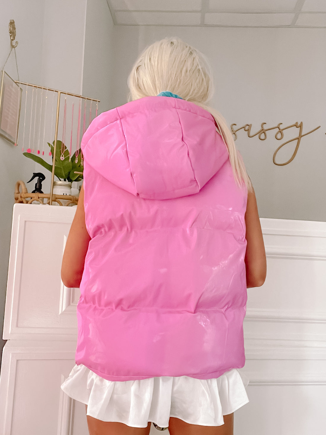Pink hooded puffer vest with shiny finish, shown from the back.
