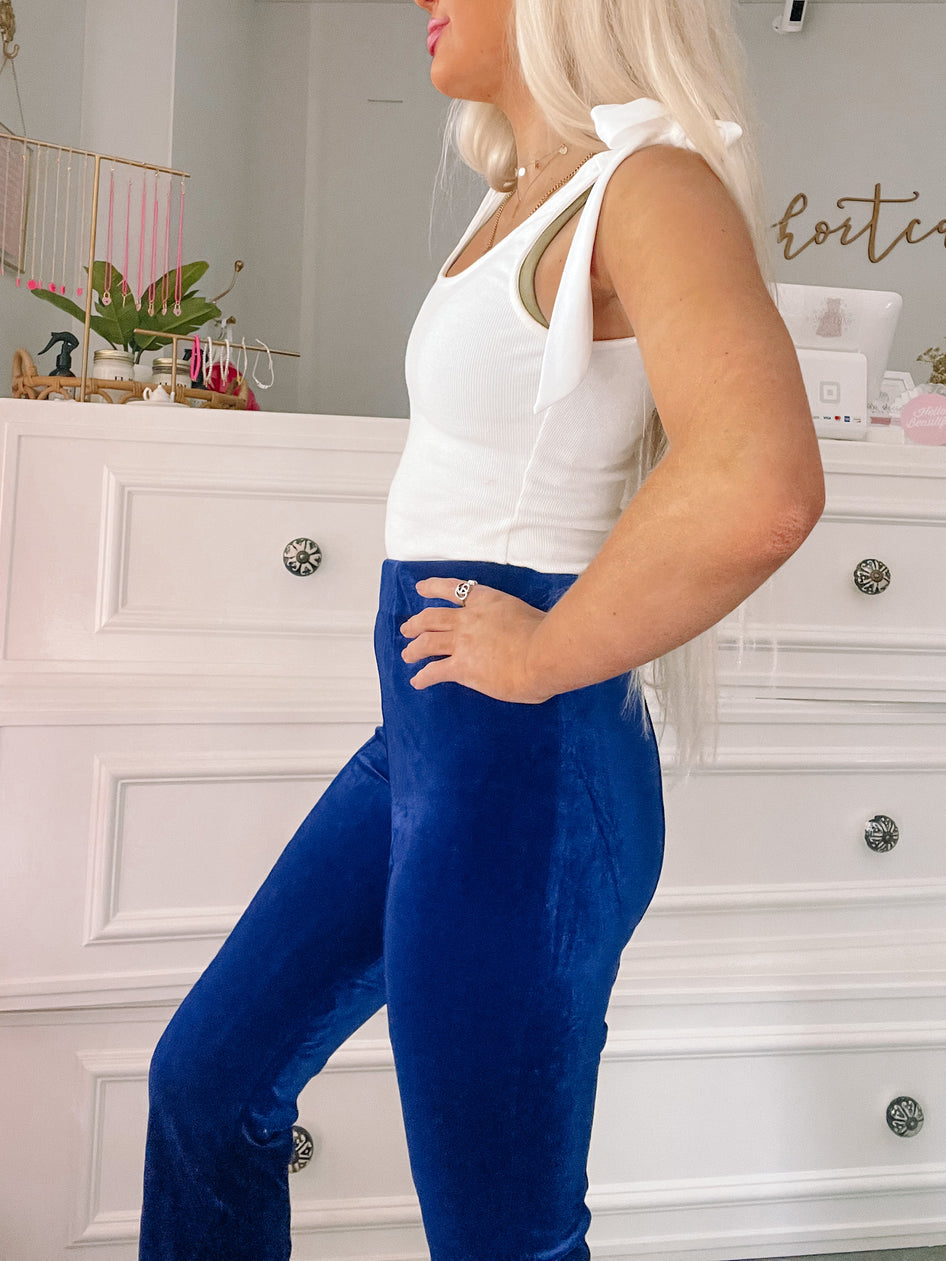Vibrant blue velvet pants in a side profile view.
