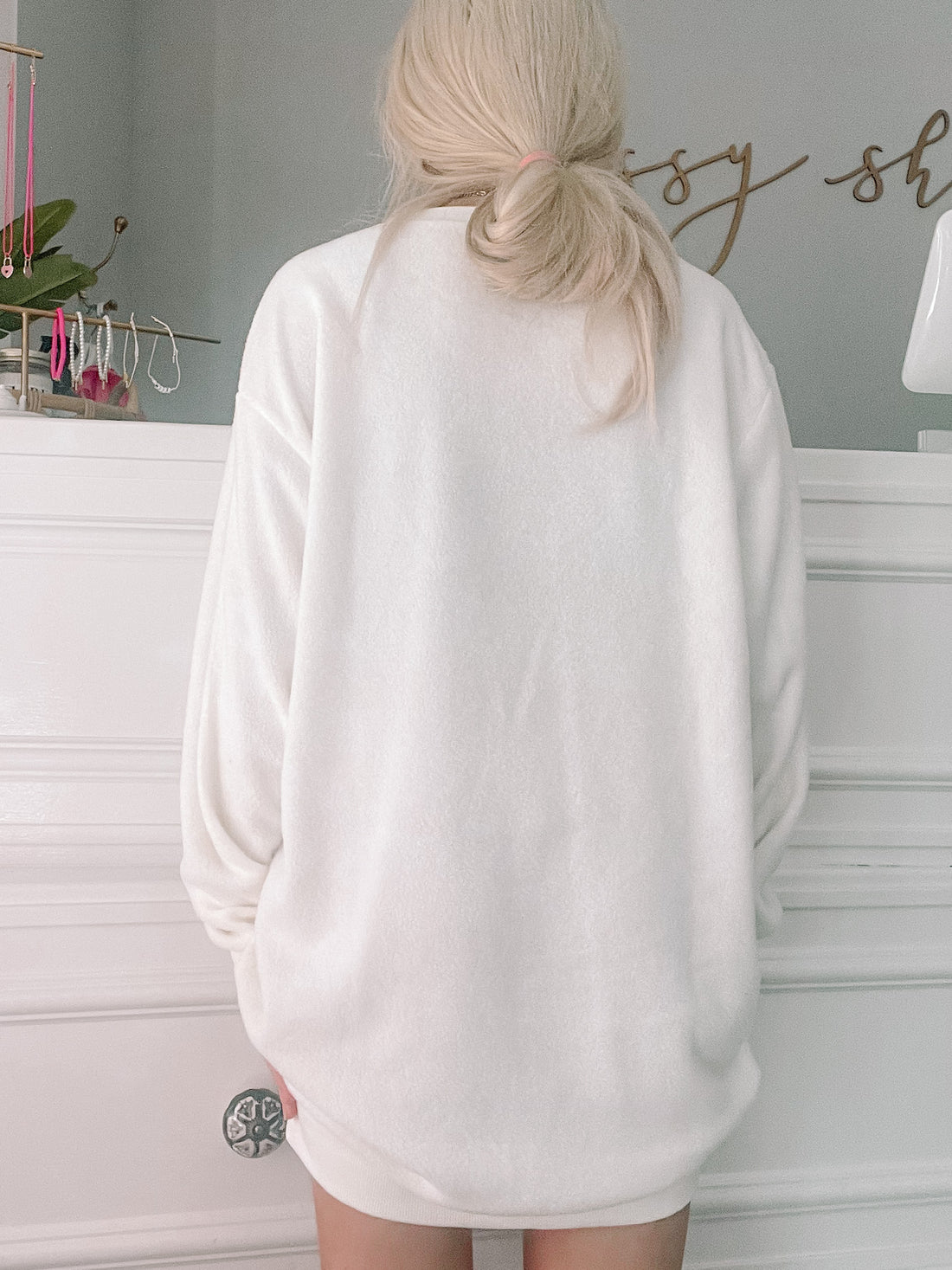 Cream-colored fleece dress shown from the back, against a white wall.
