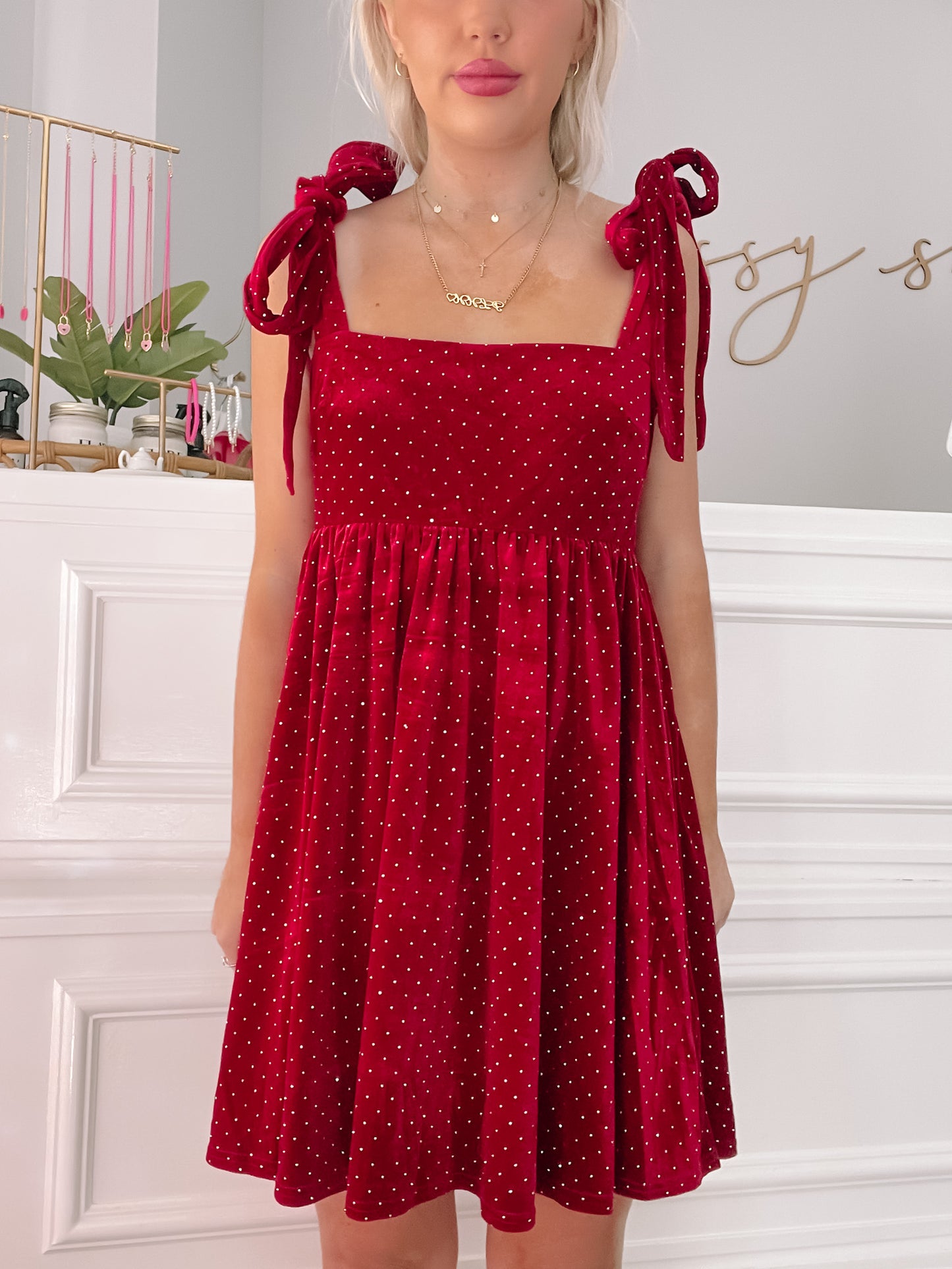 Red velvet Scarlett Letter dress with gold embellishments; tie-shoulder detail.
