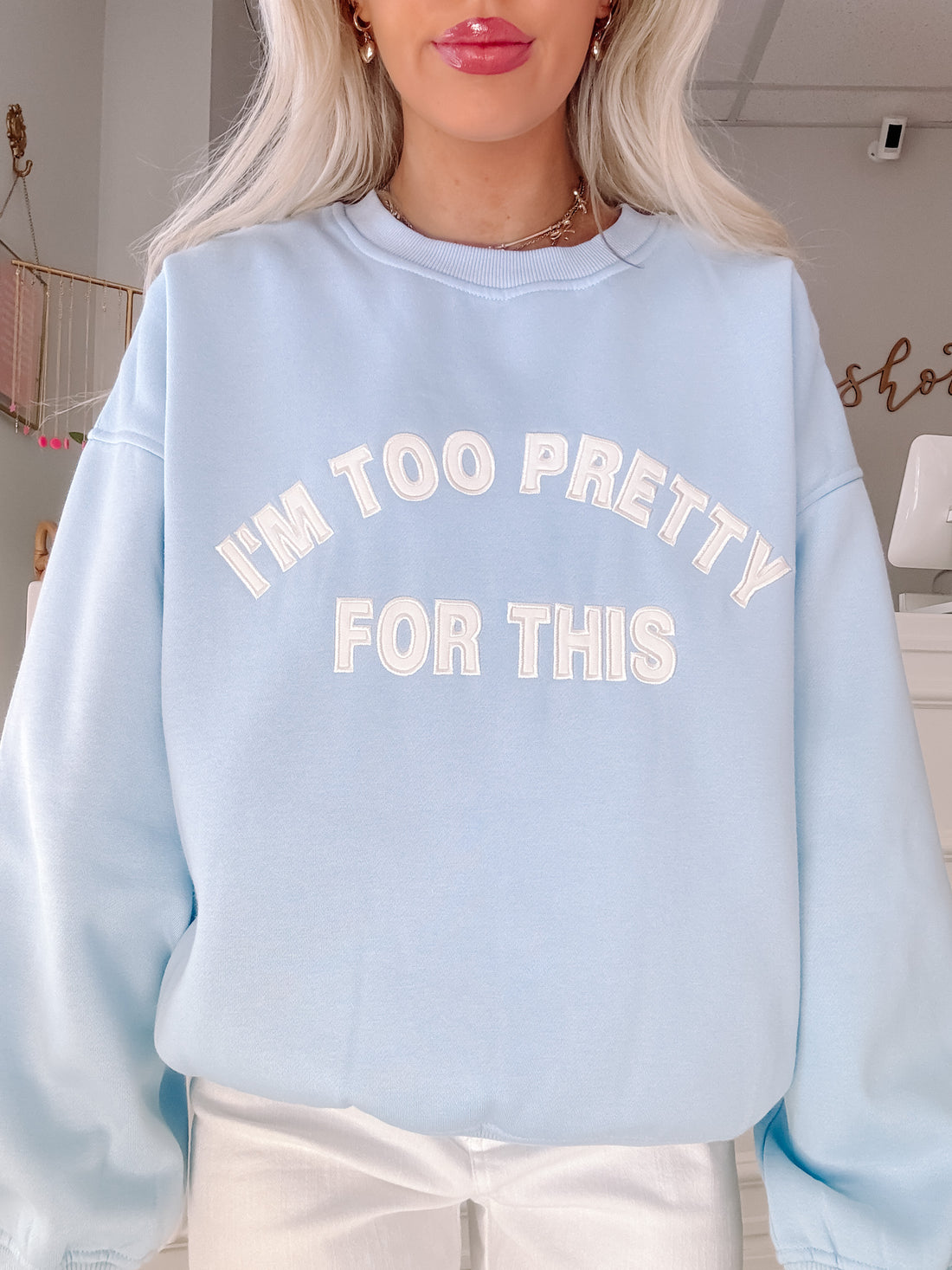 Light blue crewneck sweatshirt with "I'm too pretty for this" in white lettering.
