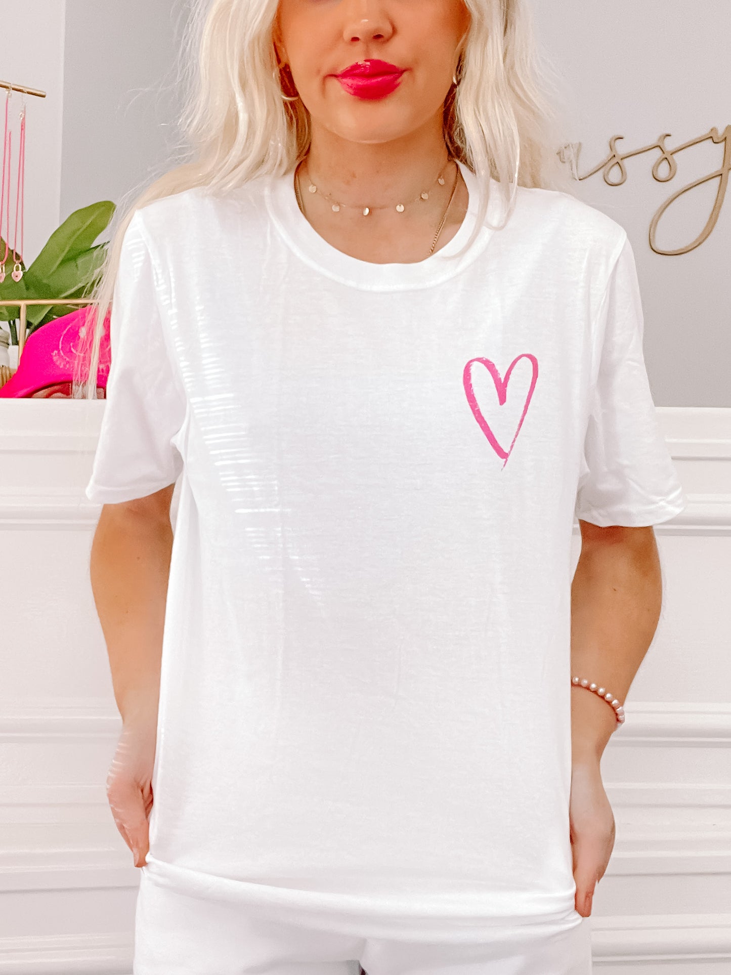 White cotton tee featuring a pink hand-drawn heart, casual style.
