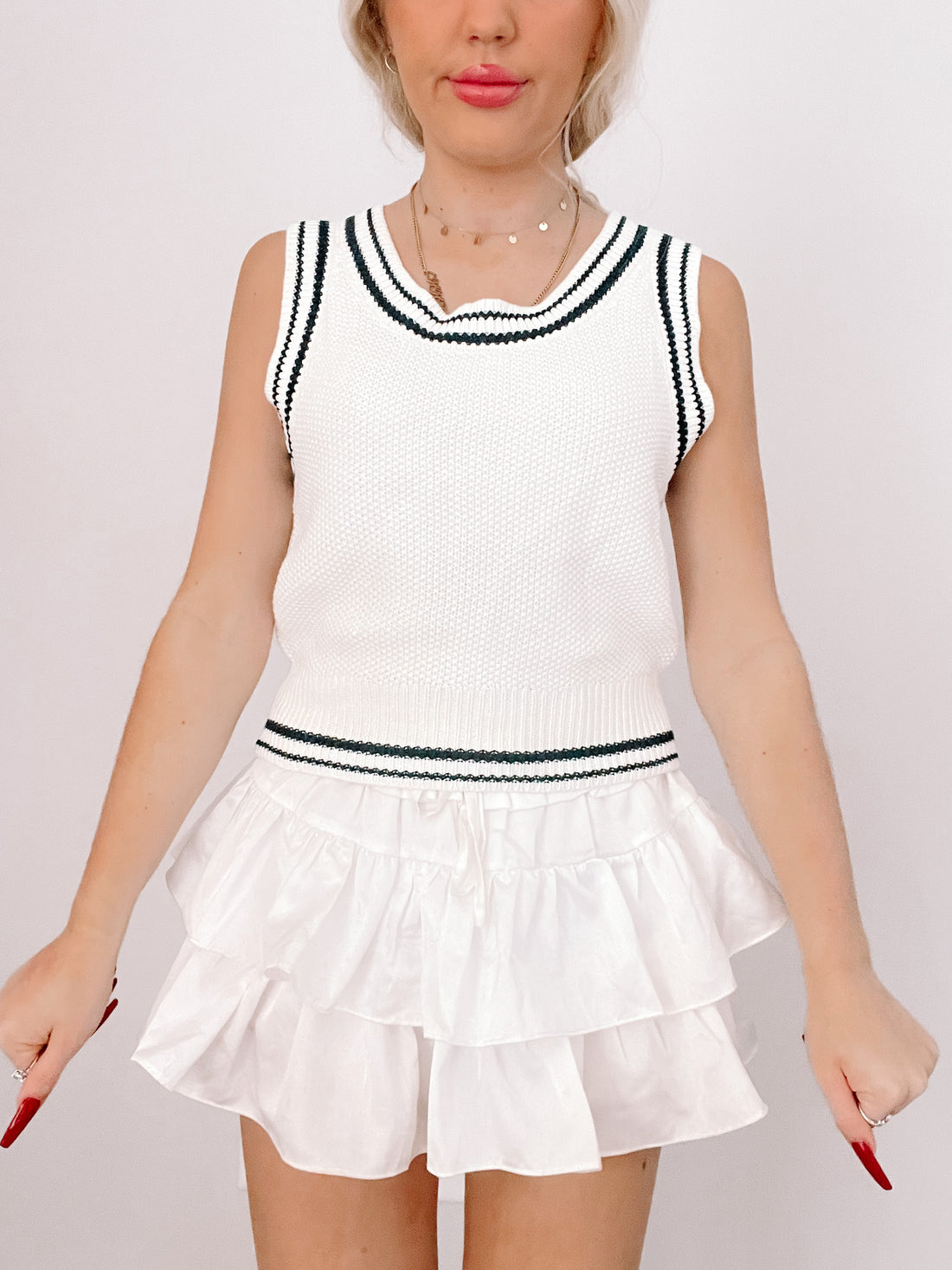 White knitted sleeveless sweater top with navy blue trim
