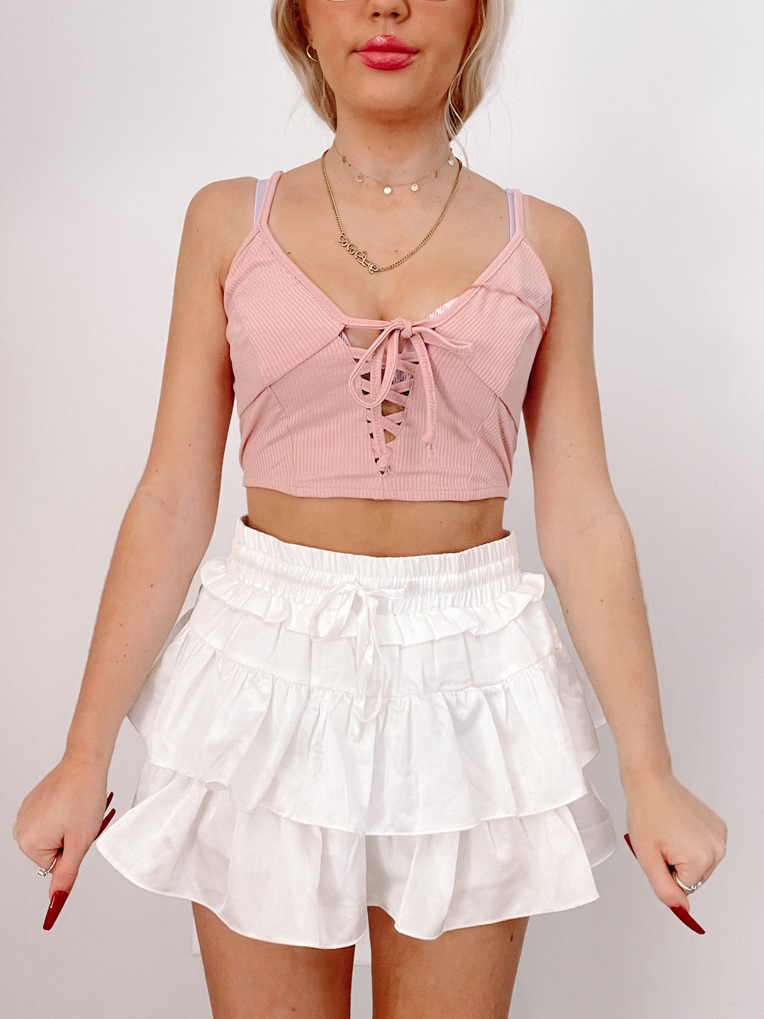 White tiered ruffle mini skirt and pink lace-up crop top outfit
