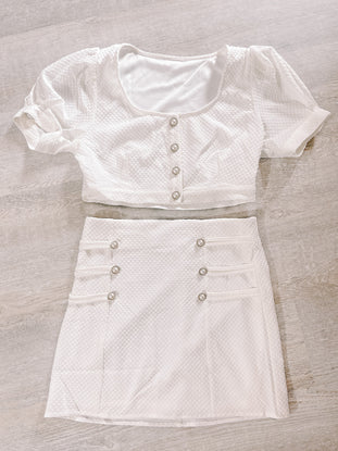 White textured two-piece outfit:  cropped button-front top & mini skirt.
