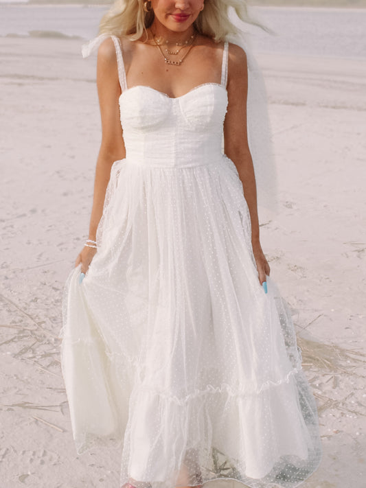 White polka dot midi dress on a sandy beach.