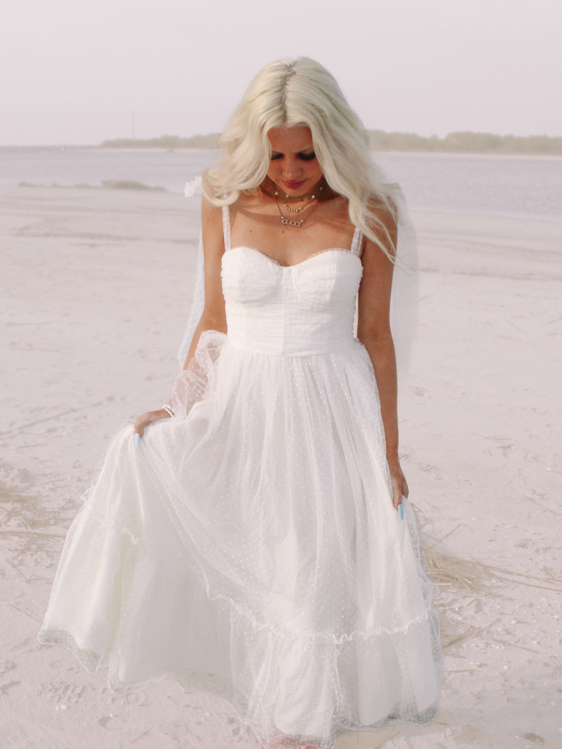 White polka dot tulle maxi dress on a beach.
