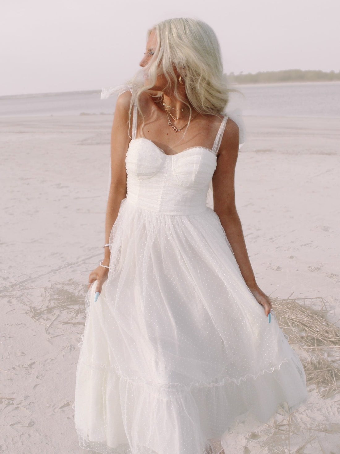 White polka dot midi dress on a beach.
