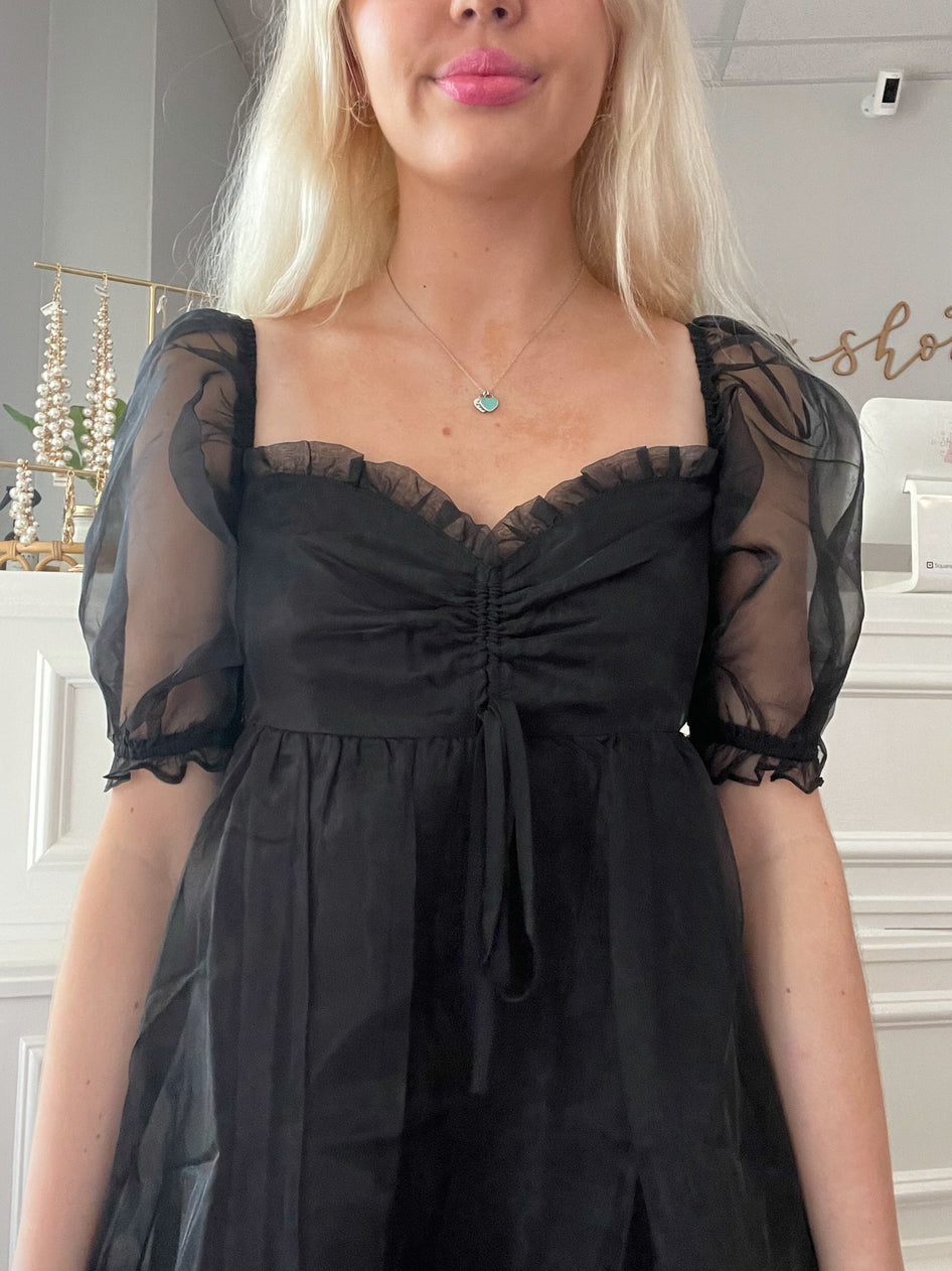 Black sheer-sleeved mini dress with drawstring bodice detail.
