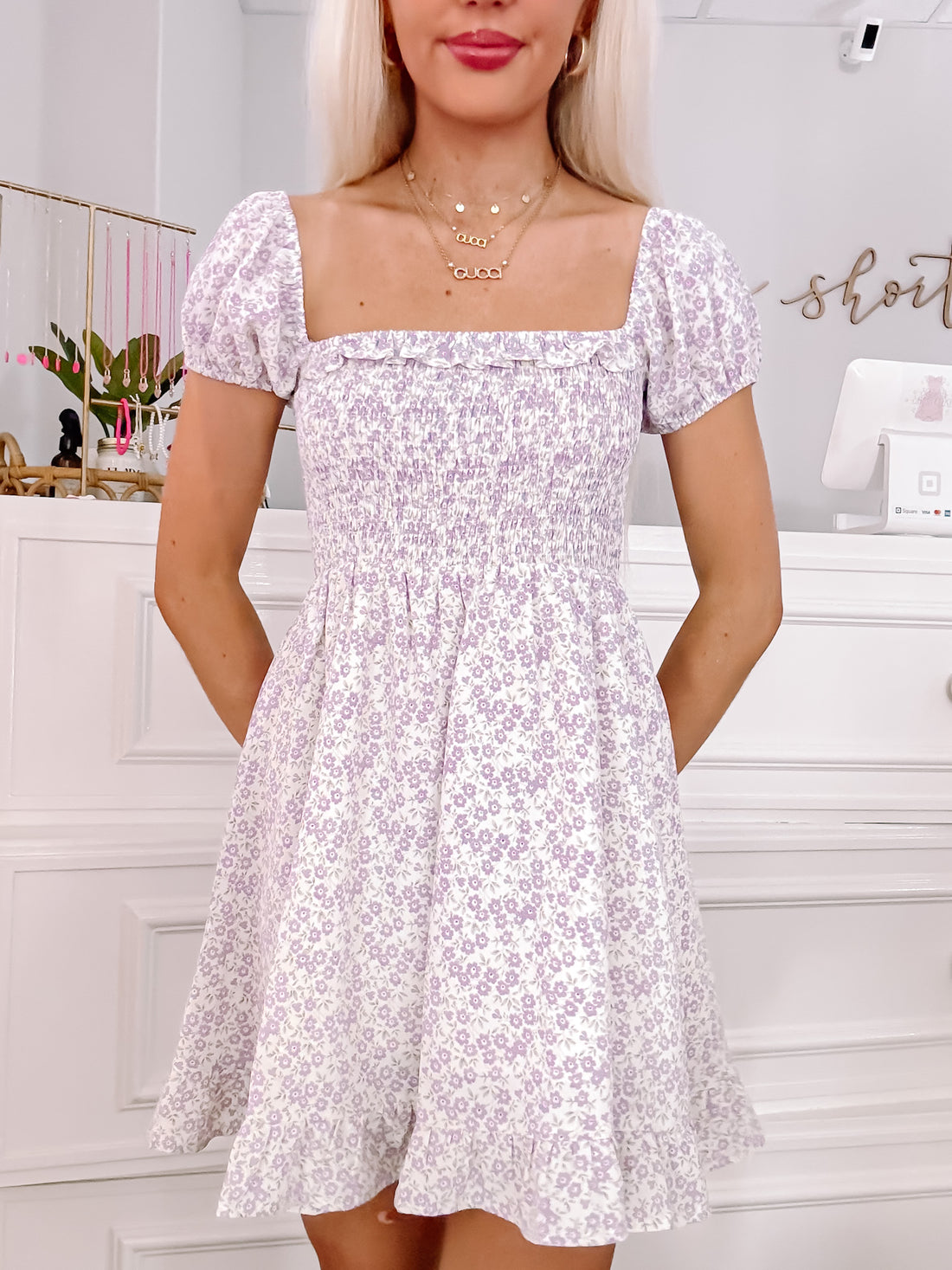 Lilac floral mini dress with puff sleeves and smocked bodice, shown on model.
