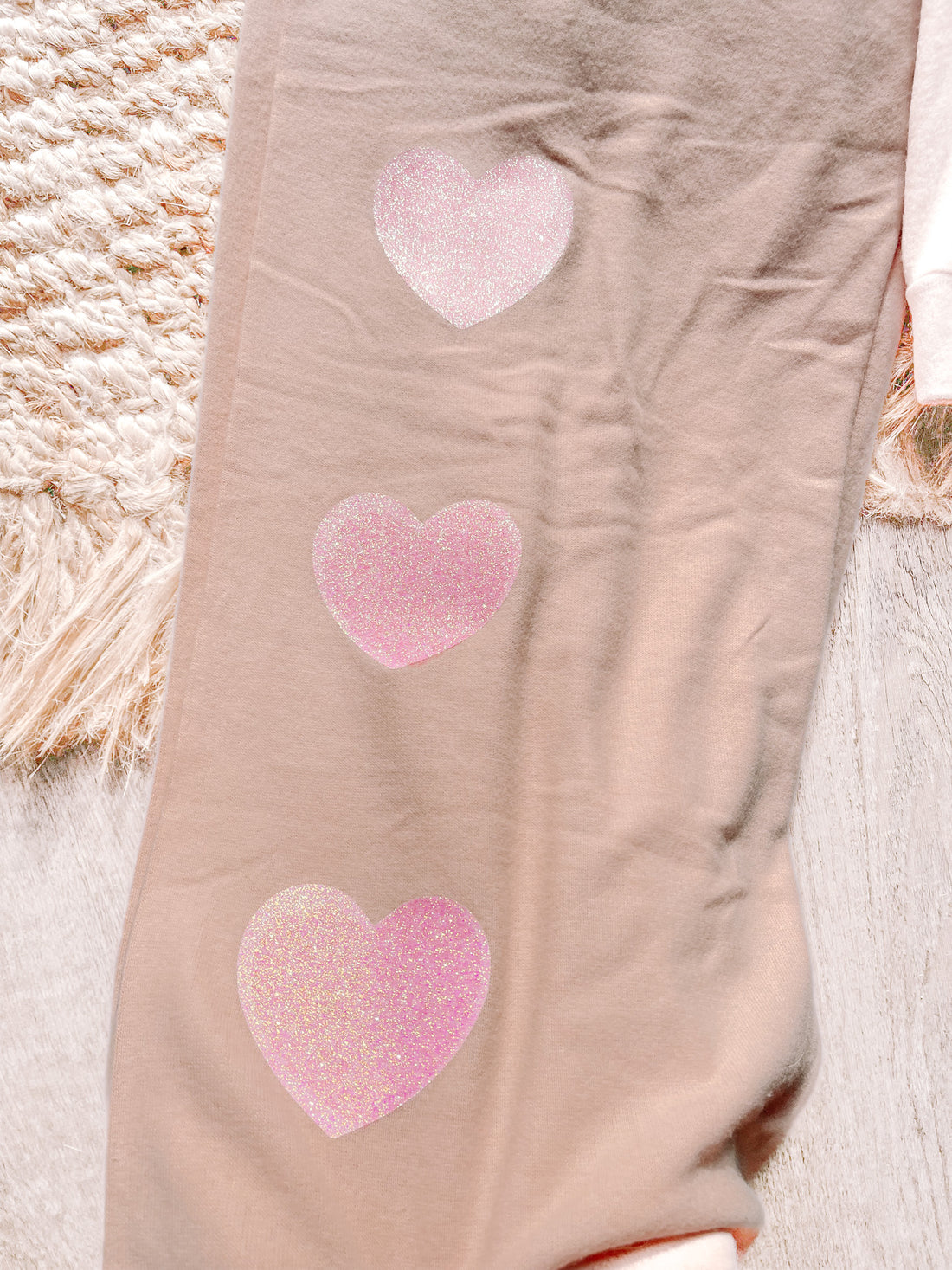 Beige pajama pants with pink glitter hearts, cozy feel.
