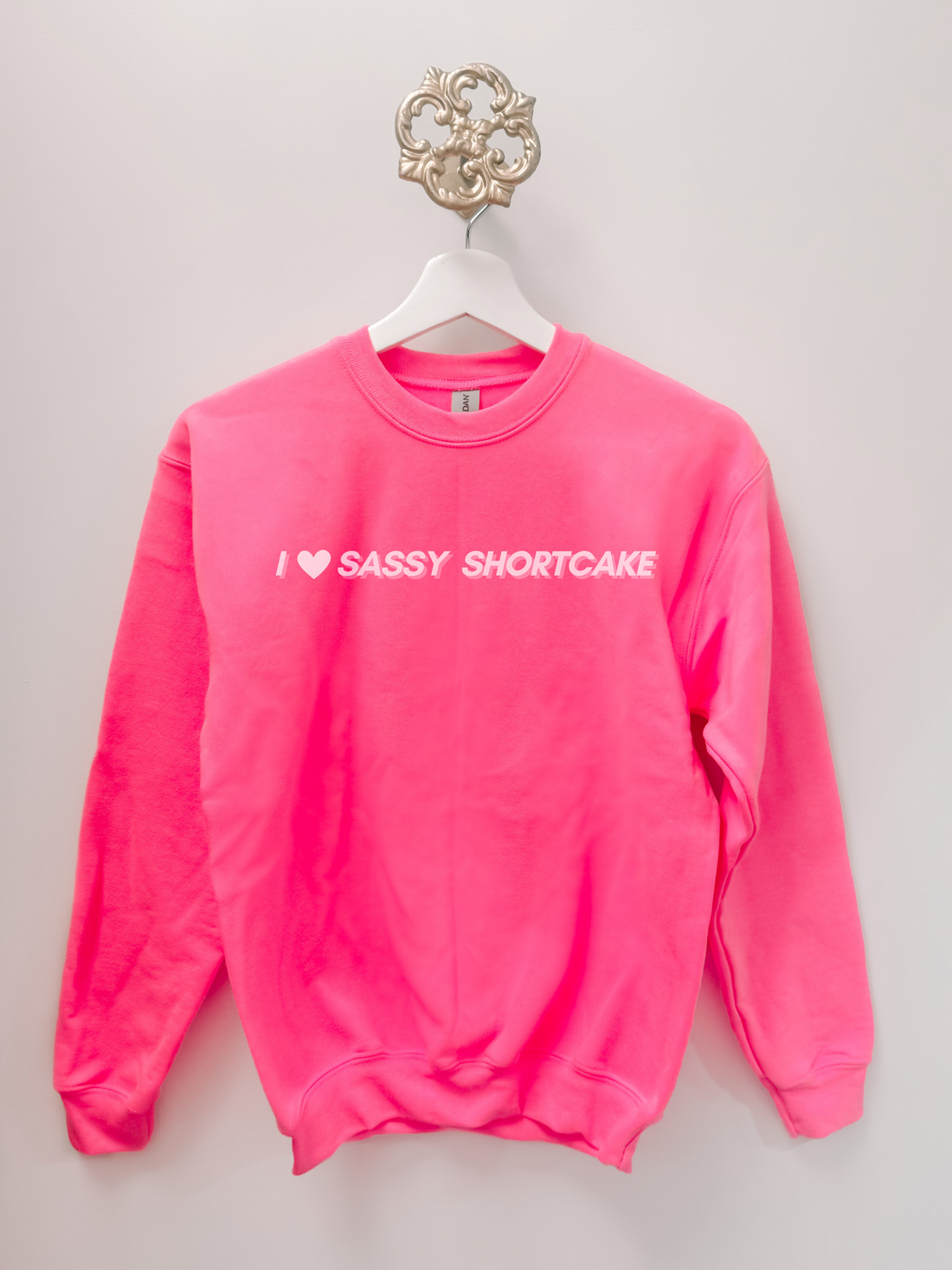 pink sweatshirt with white heart and Sassy Shortcake script, sleeves extended.