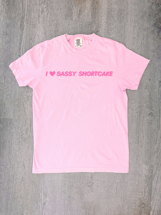 Pastel pink bow tee laid flat, red heart and Sassy Shortcake - I heart sassy shortcake merch tee