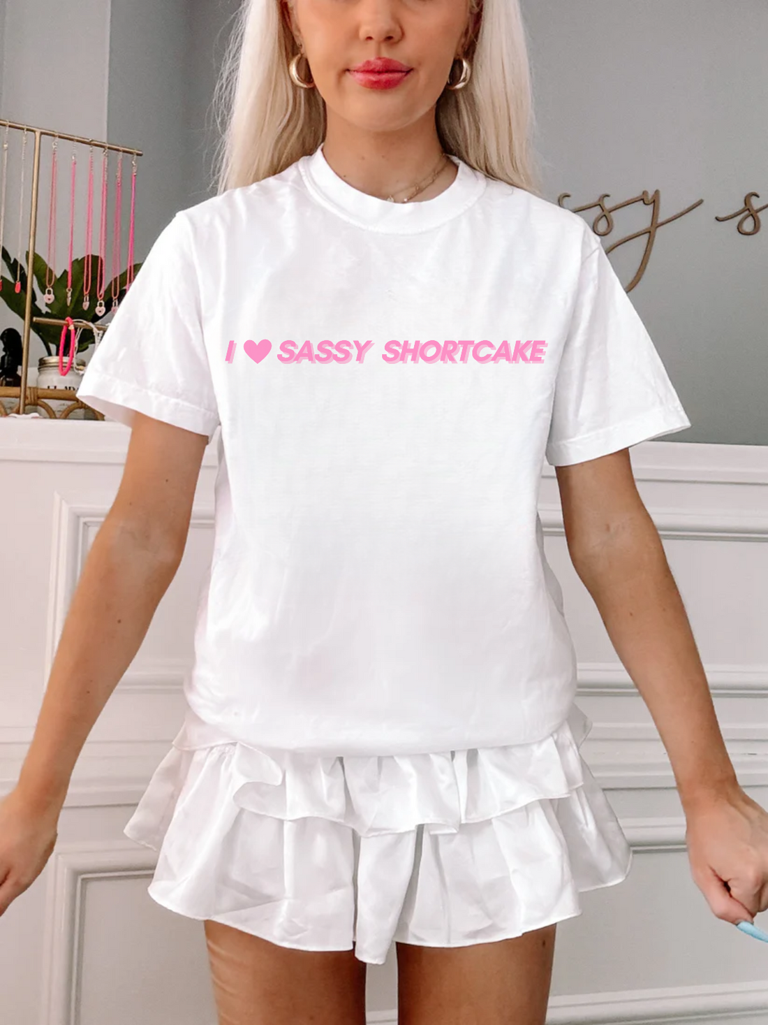 Model wearing white tee with pink I heart Sassy Shortcake graphic, against plain white background.