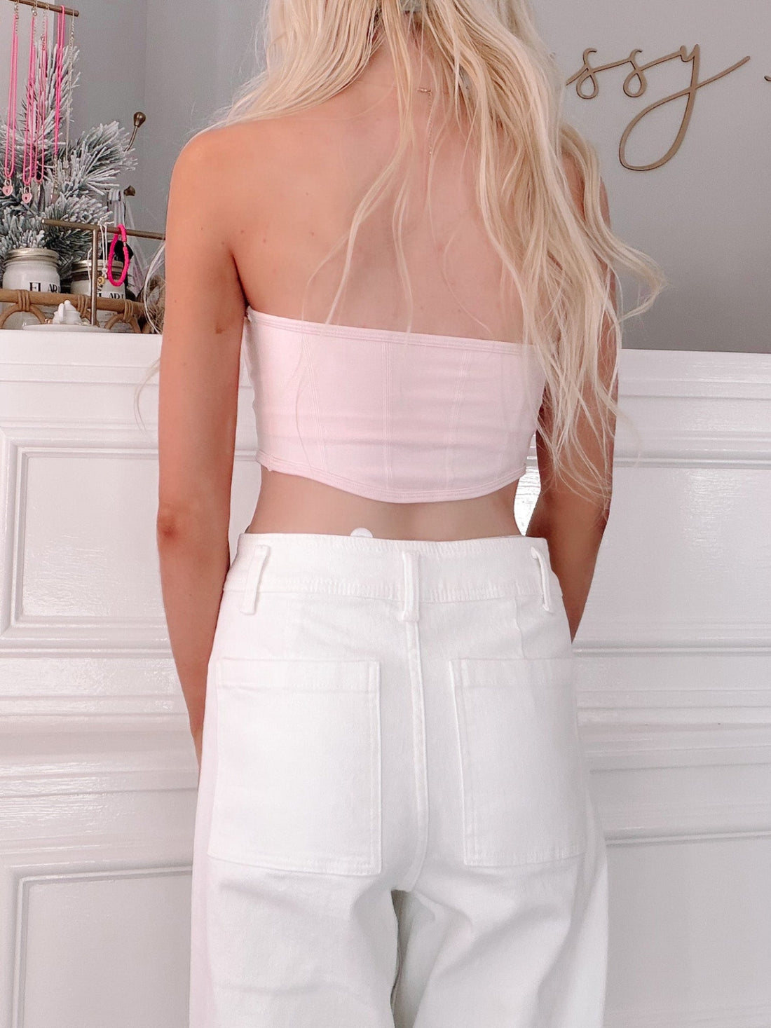 Pink Bandeau Top from Sassy Shortcake - Person wearing a light pink tube top and white pants in a minimalistic room.