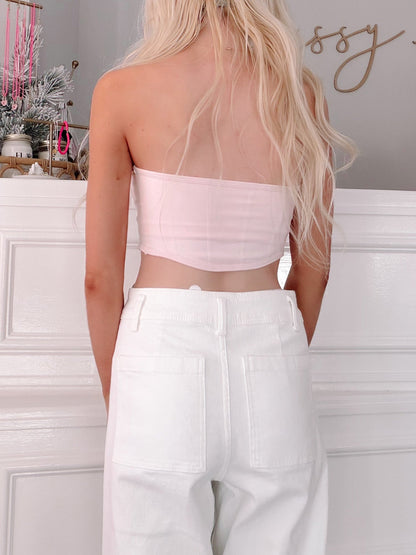 Pink Bandeau Top from Sassy Shortcake - Person wearing a light pink tube top and white pants in a minimalistic room.