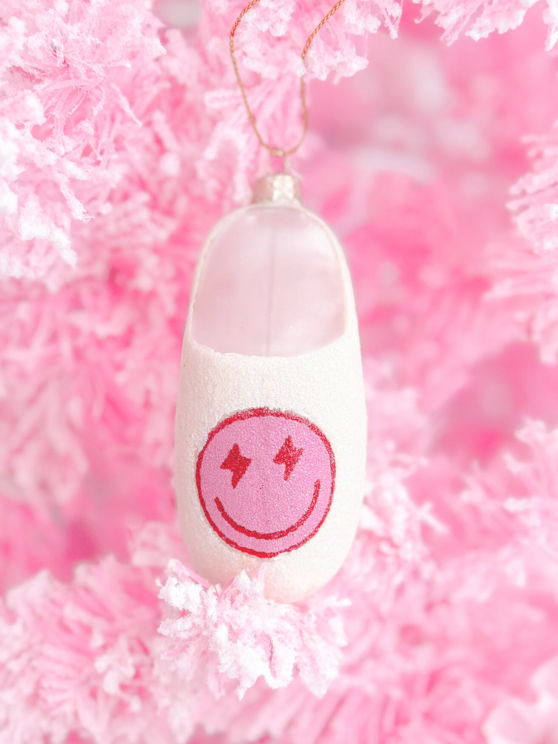 Pink glass slipper Christmas ornament with smiley face.
