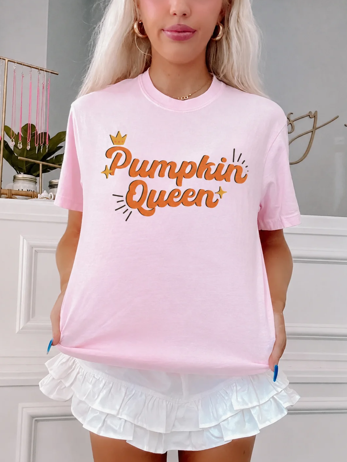 Close-up of the Pumpkin Queen Tee by Sassy Shortcake showing the orange retro script, gold crown, and sparkle graphic on the light pink tee.