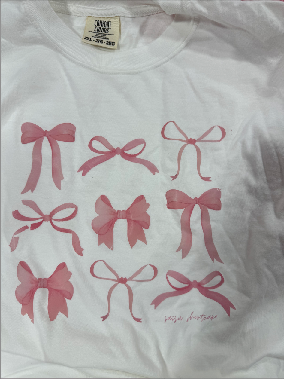 White t-shirt featuring a pink ribbon design.
