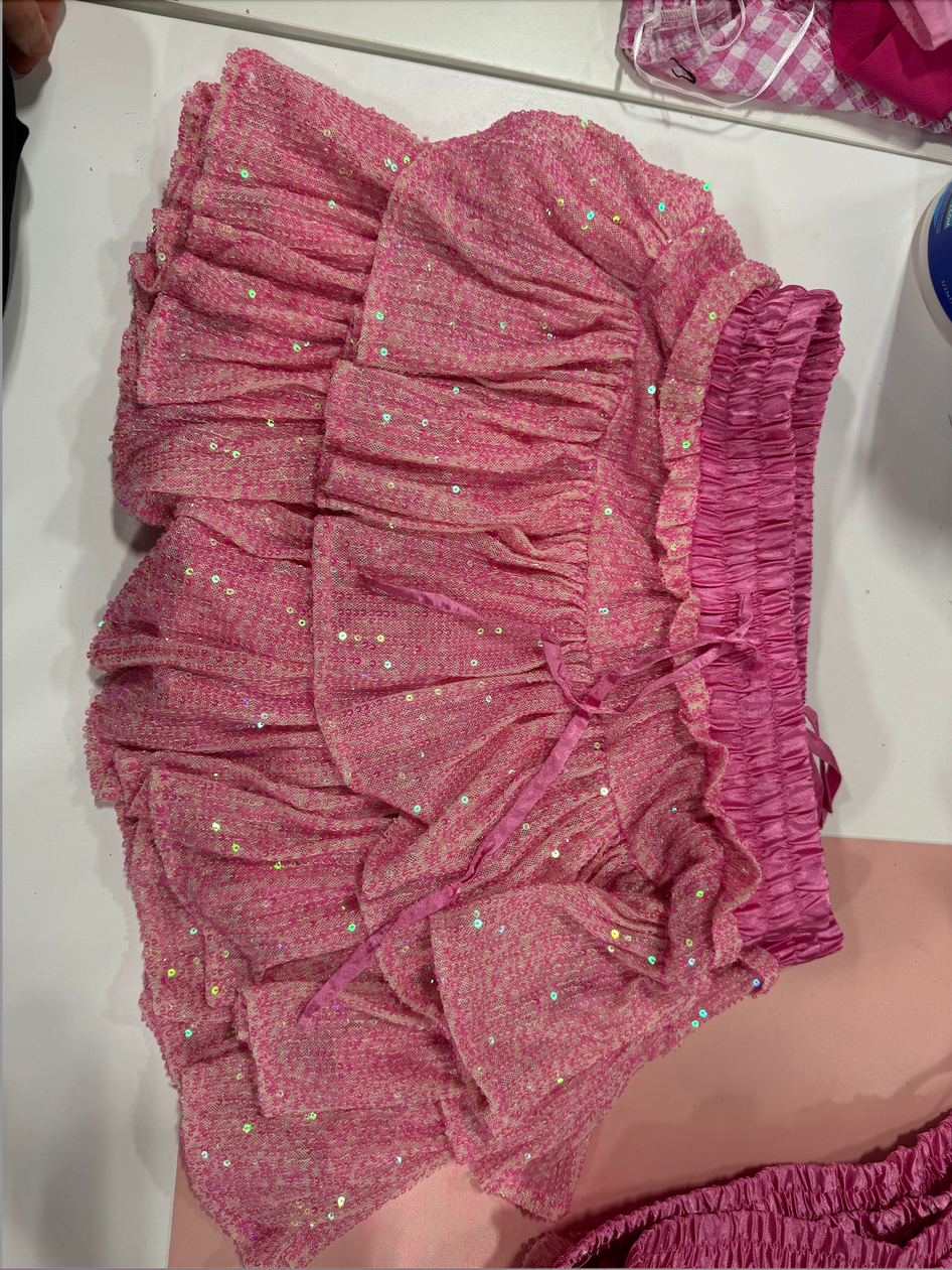 Pink sequined mini skirt with ruffled layers and a drawstring waist.
