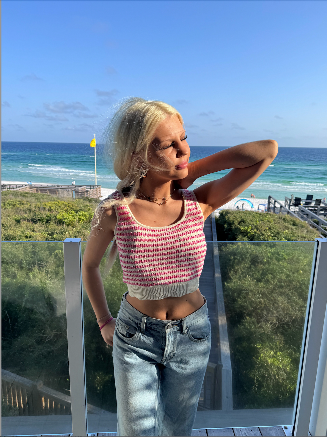 Cream and pink striped knit crop top worn outdoors near the beach.
