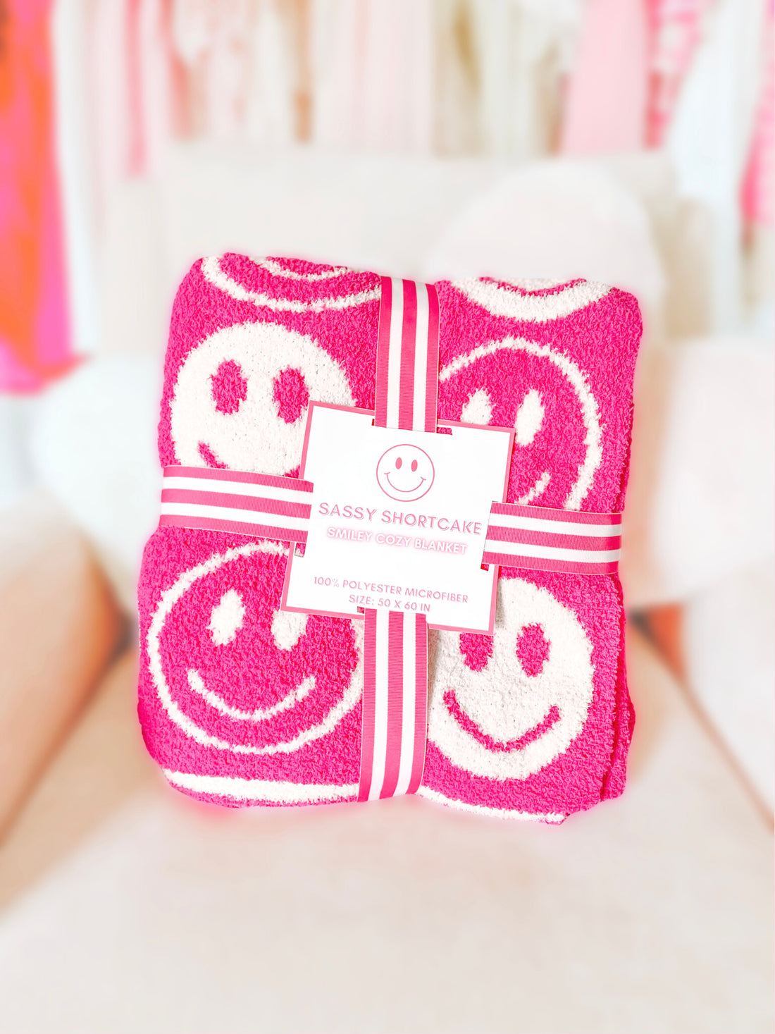 Pink microfiber blanket with white smiley faces, 50x60 inches, wrapped with ribbon.
