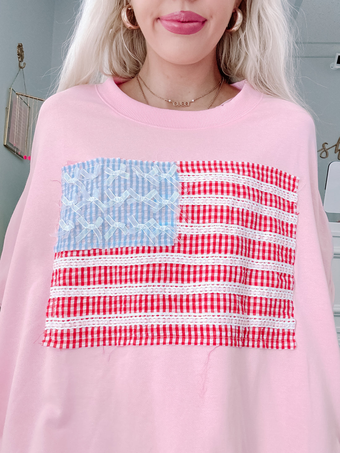 Close-up of flag patch and metallic bows on Stars & Stitches Pink Crewneck.