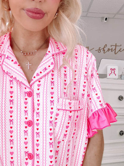 Struck by Love Set by Sassy Shortcake – close up of hearts and bows stripe print with pink buttons, pocket detail, and ruffle sleeve