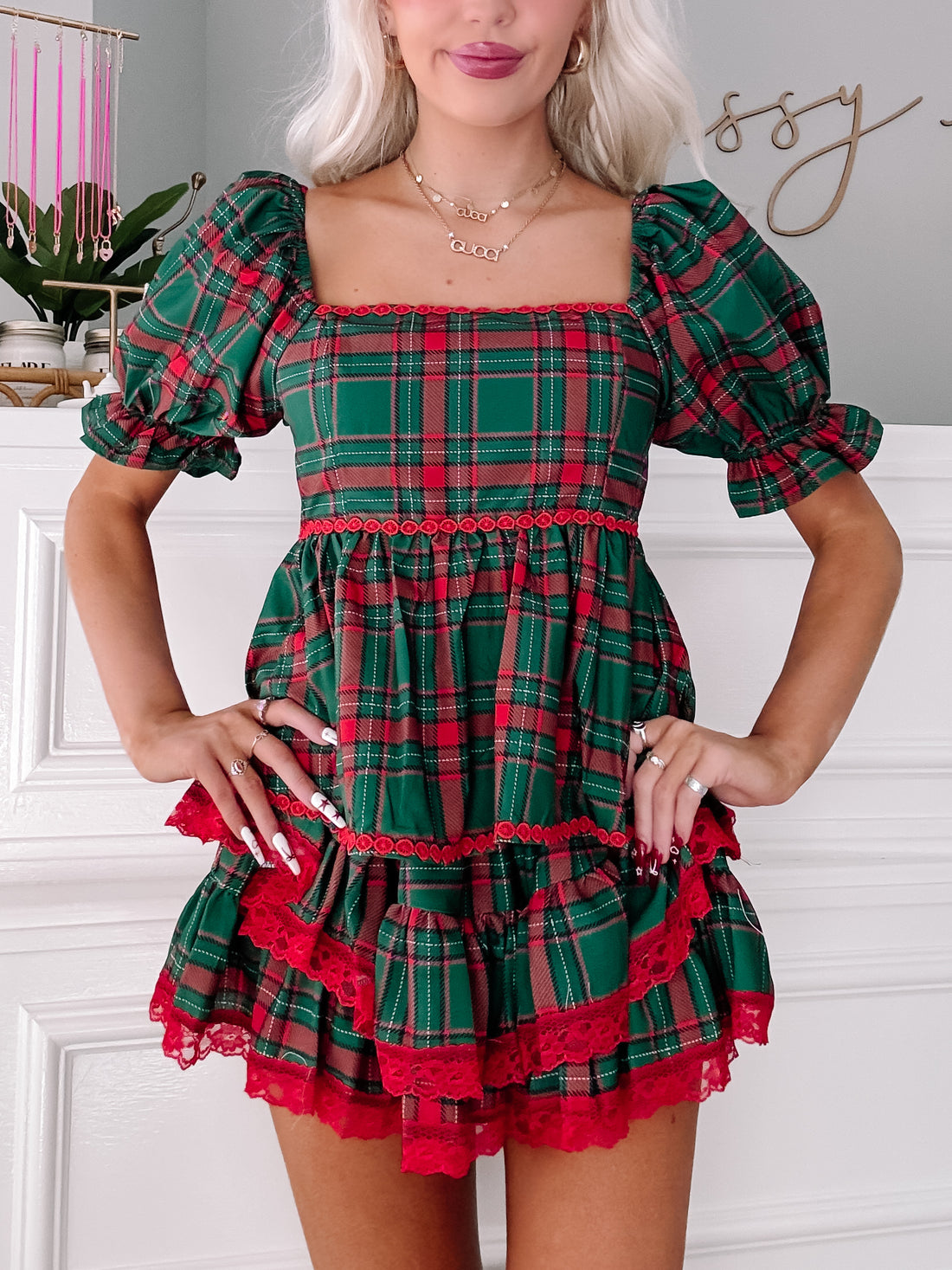 Red and green plaid mini dress with puff sleeves and layered red lace trim.
