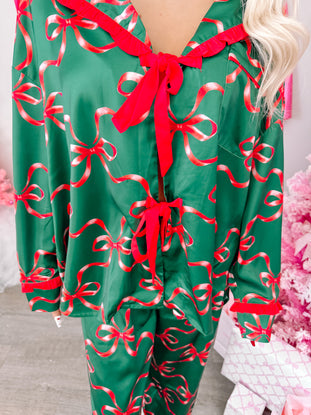 Green satin pajama set adorned with festive red ribbons and bows, perfect for cozy holiday nights.
