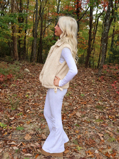 Close-up of the Sassy Shortcake Vanilla Bean Bow Vest showing the soft cream sherpa texture, snap buttons, and bow.
