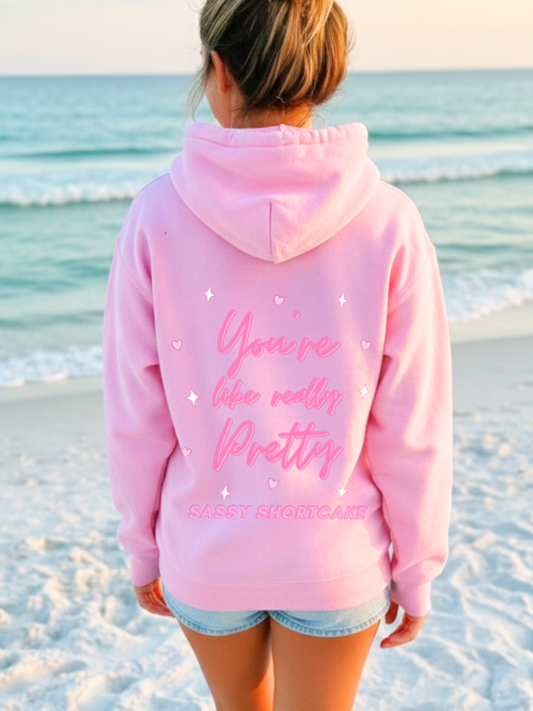 You're Like Really Pretty Hoodie from Sassy Shortcake - Person wearing a pink hoodie with text on the beach