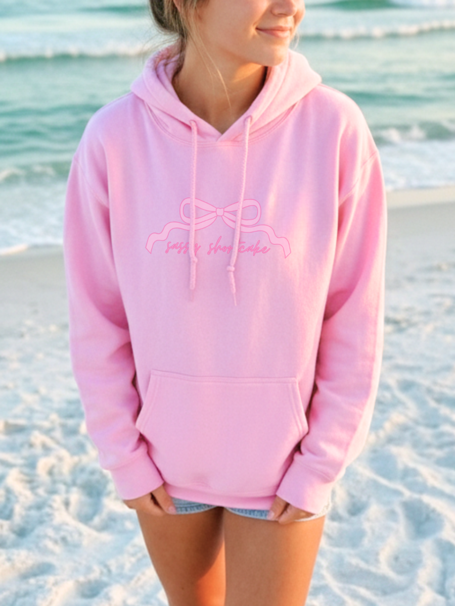 You're Like Really Pretty Hoodie from Sassy Shortcake - Person wearing a pink hoodie with a logo on a beach