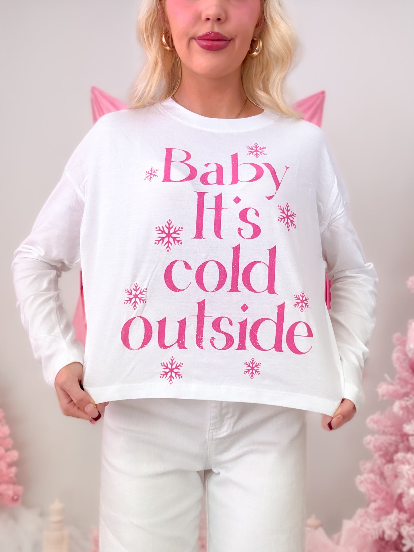 Model wearing a white t-shirt featuring a hot pink graphic of snowflakes and the phrase "Baby It's Cold Outside."