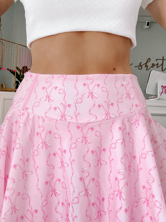 Model posing in pleated pink golf skirt with stretch fabric