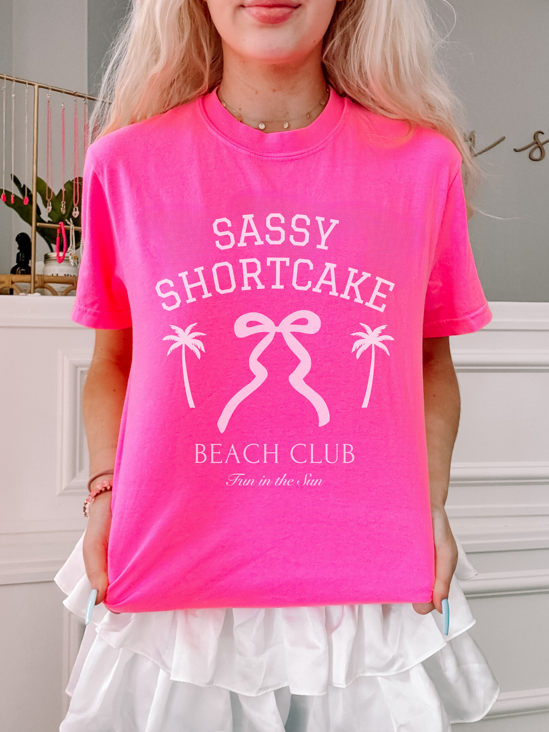 Front view of a model in the pink Sassy Shortcake tee featuring a white bow logo, posed on white background.