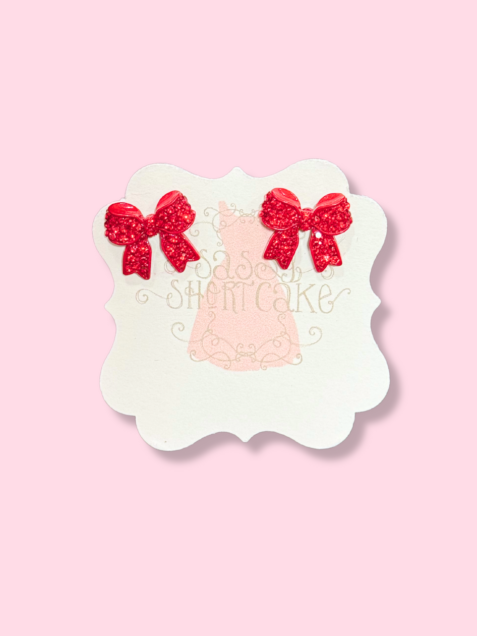 Red bedazzled bow earrings on display
