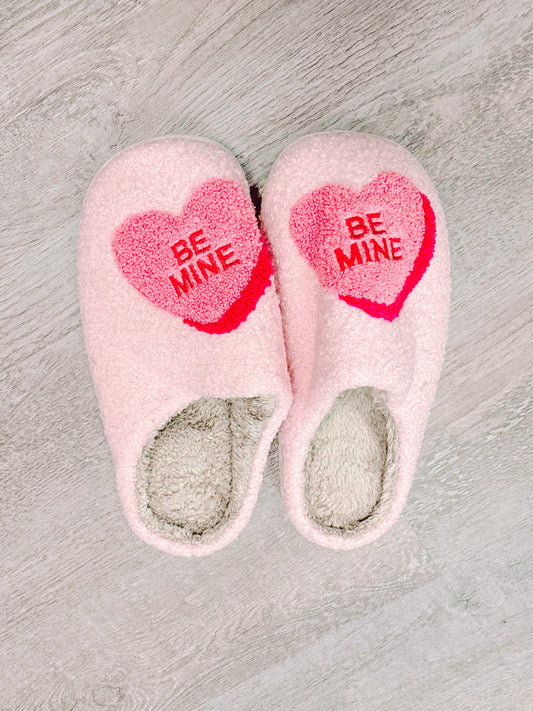 Pink "Be Mine" heart slippers, cozy plush fabric.
