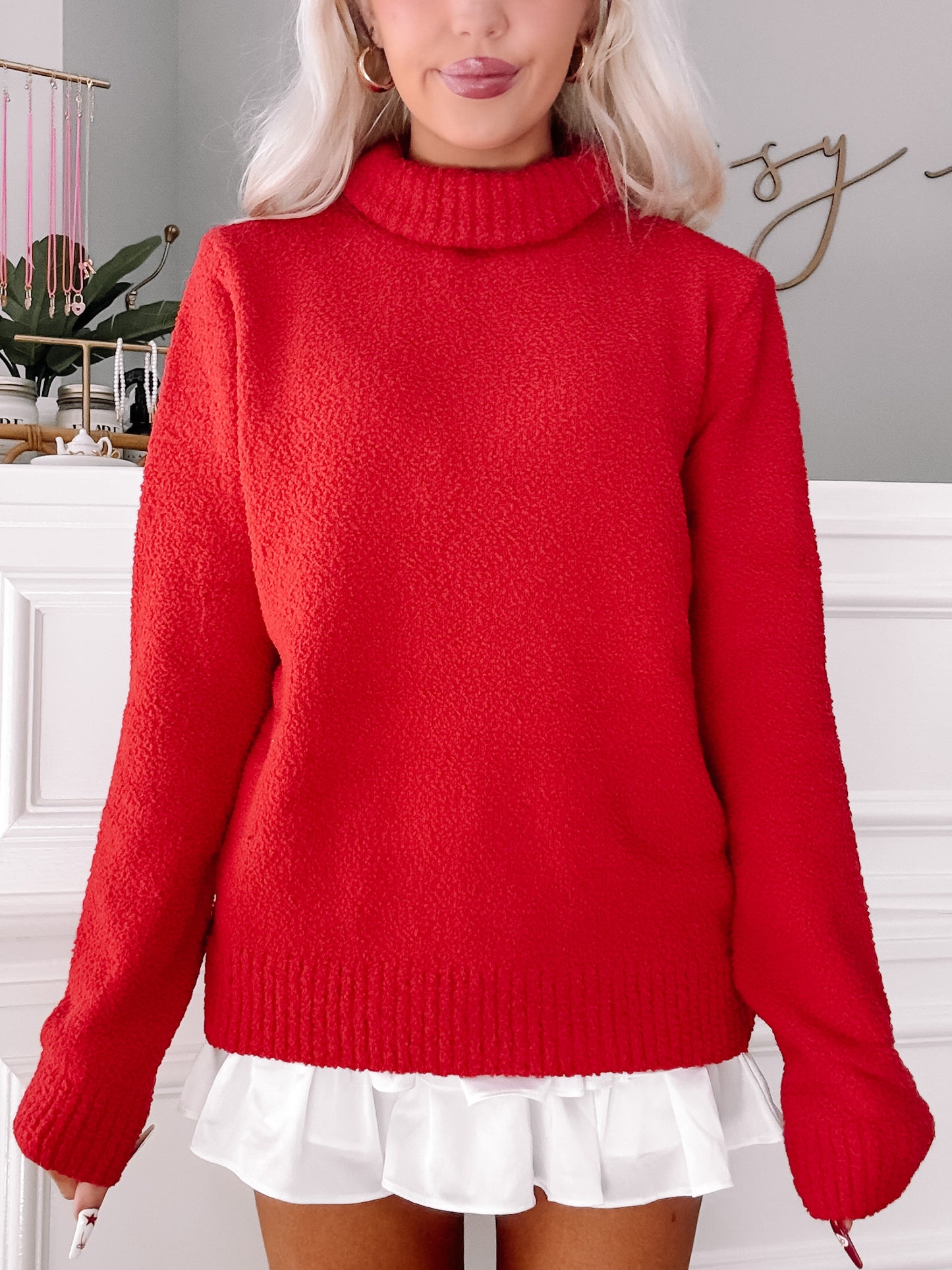 Red textured turtleneck sweater styled with a white ruffle skirt.
