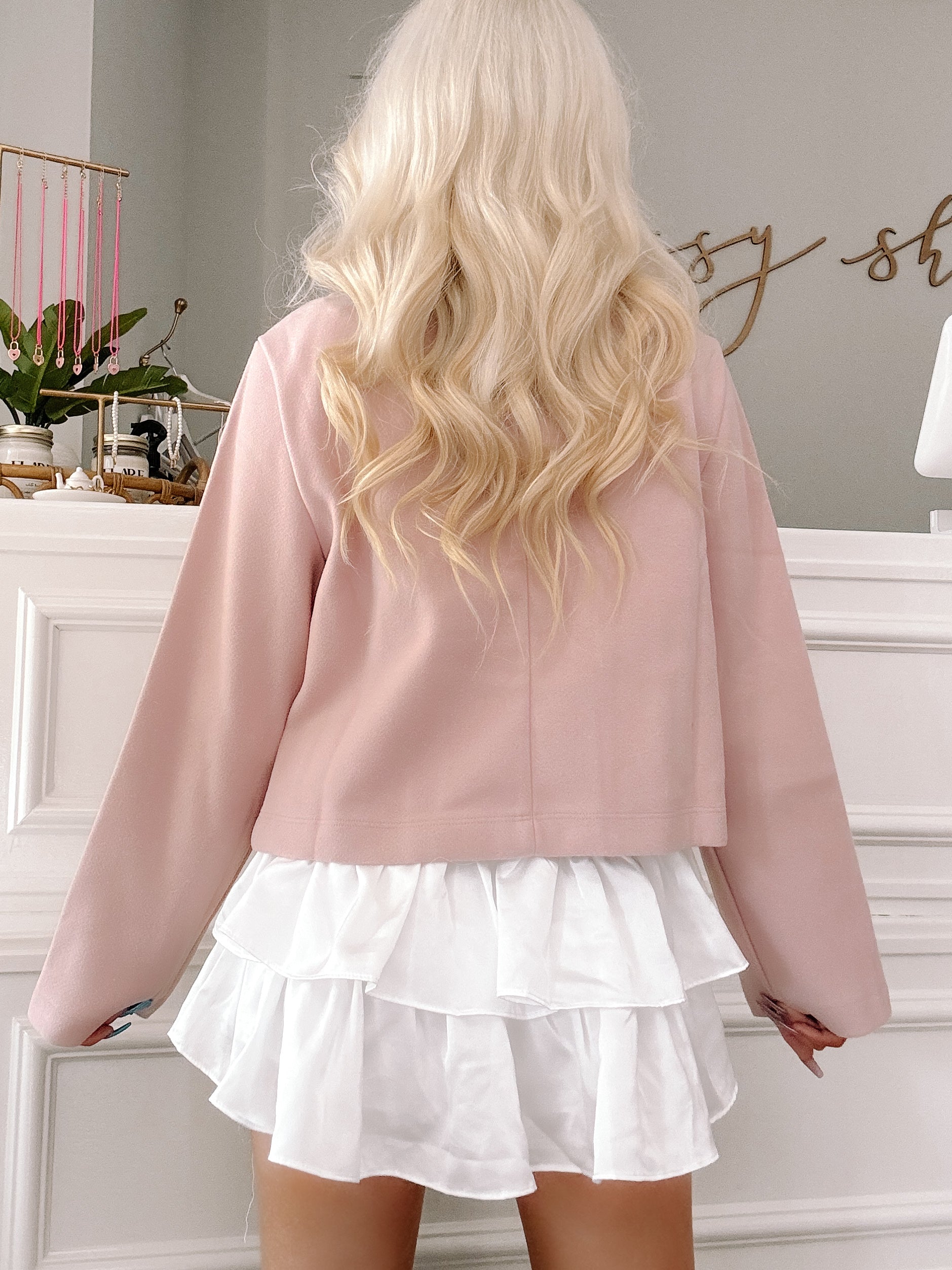 Dusty rose cropped blazer styled with a white ruffled mini skirt.
