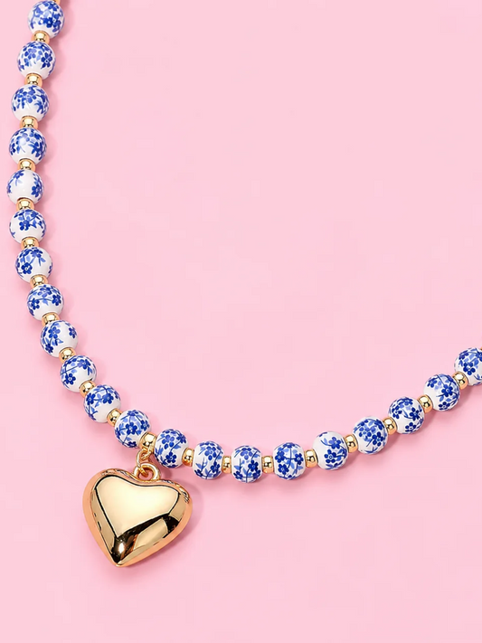 Blue Belle Heart Necklace from Sassy Shortcake - A beaded necklace featuring blue and white round beads with a polished gold heartshaped pendant.