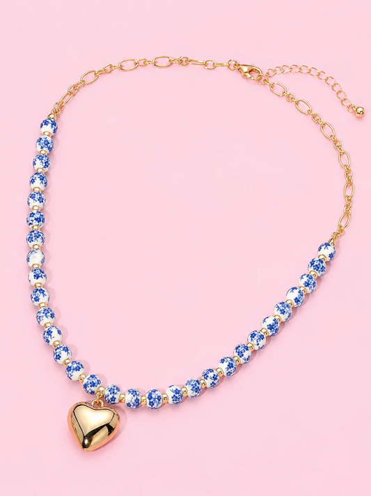 Blue Belle Heart Necklace from Sassy Shortcake - A beaded necklace featuring blue and white ceramic beads with a polished gold heartshaped pendant.