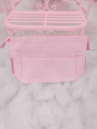 Light pink zippered pouch on a marble surface.
